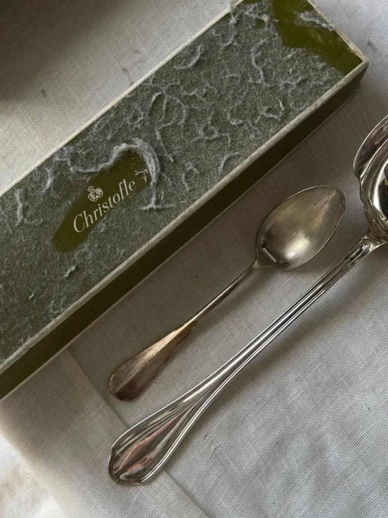 Couverts en argent anciens posés sur un tissu texturé aux tons feutrés