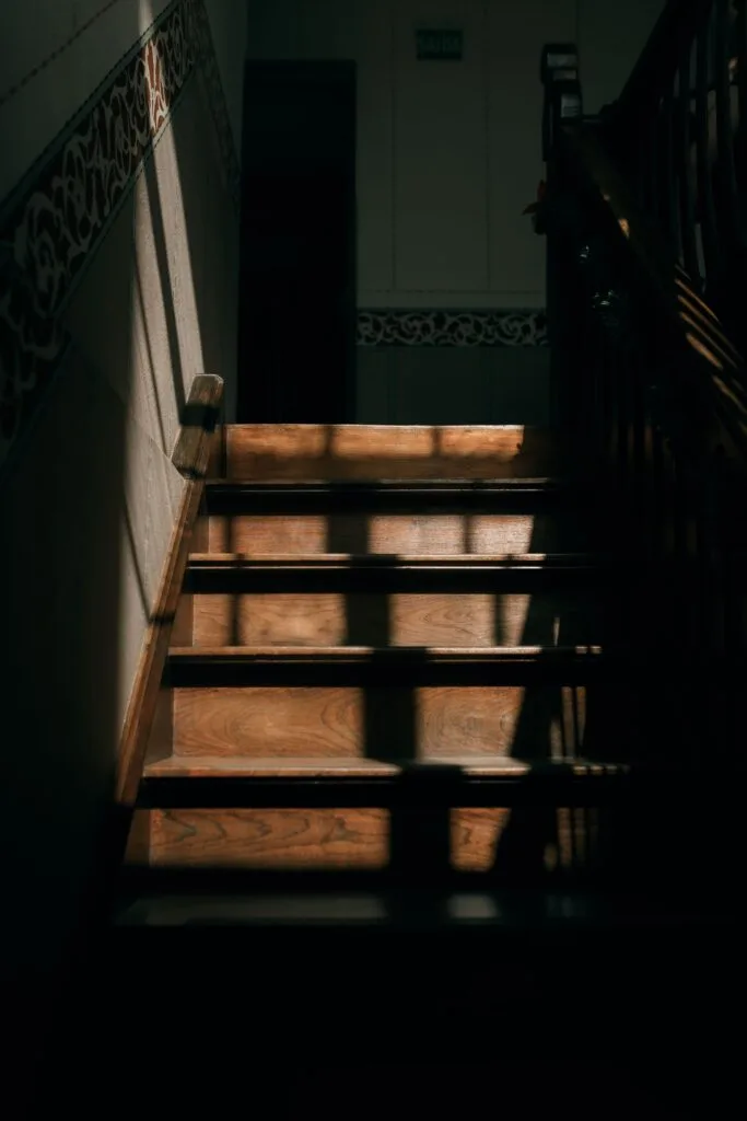 Escalier en bois ouvragé d'une maison ancienne, éclairé par une douce lumière naturelle