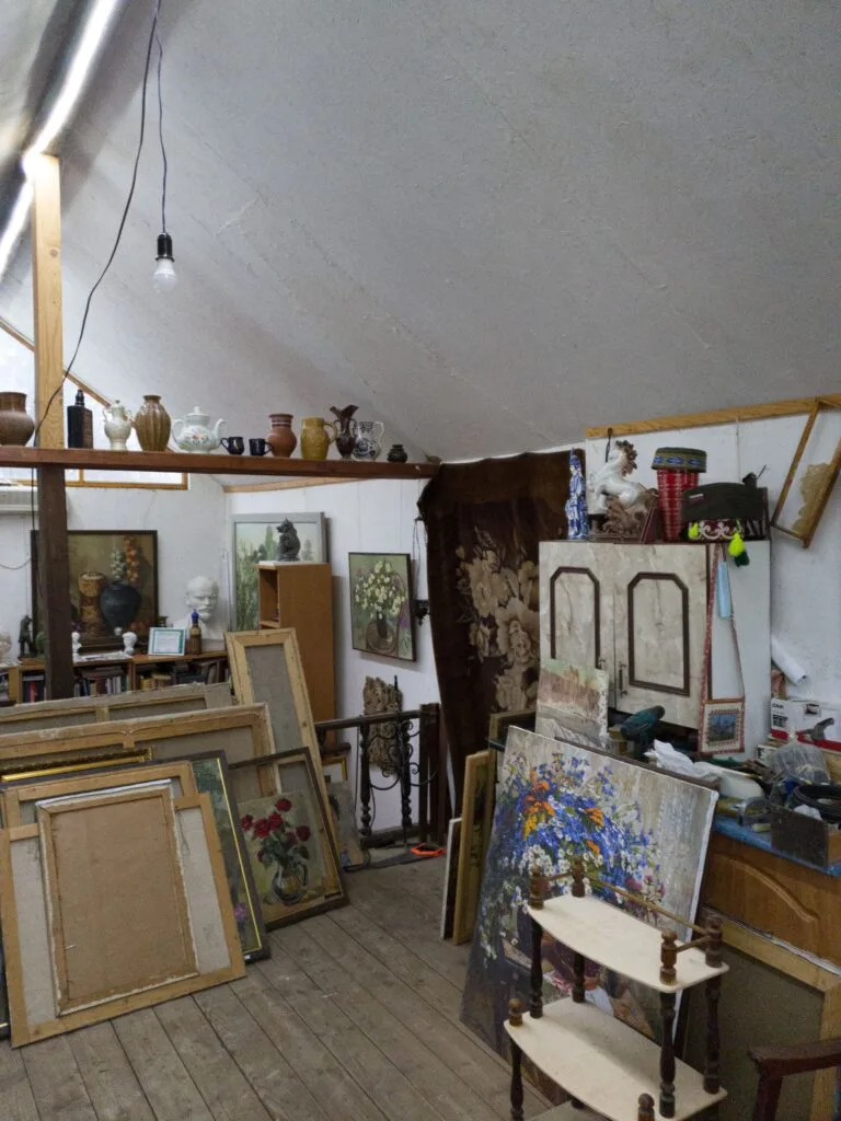 Grenier de maison de famille encombré de tableaux anciens, meubles et objets d'antiquité