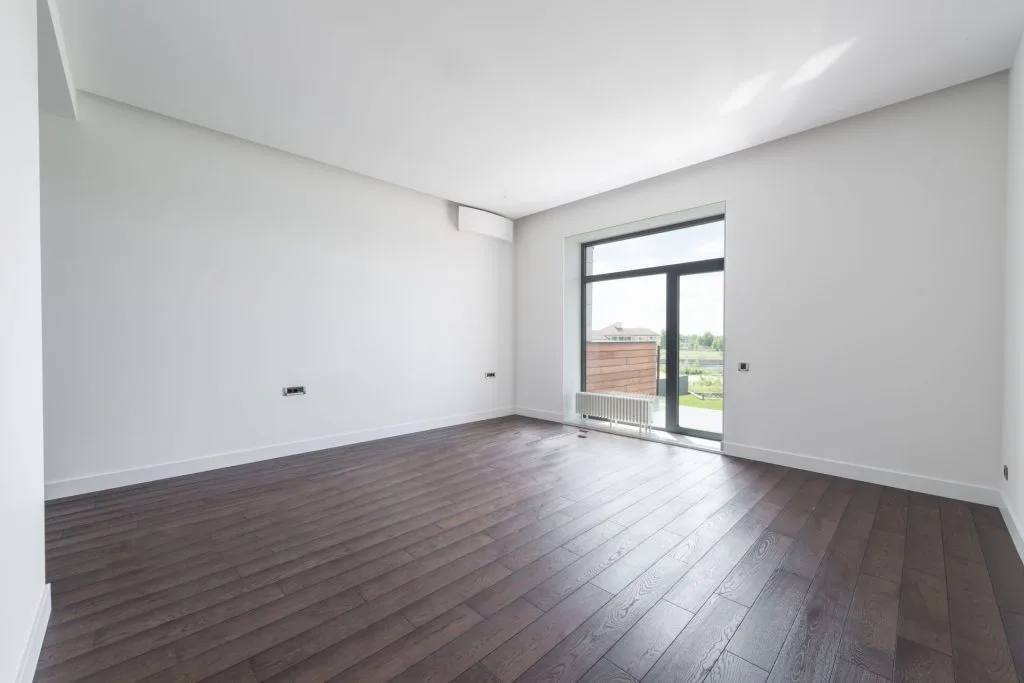 Pièce vide et lumineuse avec parquet en bois foncé
