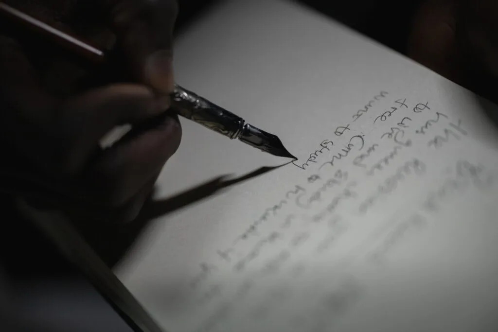 Main écrivant au stylo plume sur papier, geste soigné de prise de notes d'inventaire